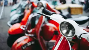 Plusieurs scooters de ville stationnés en rangée dans une rue urbaine.