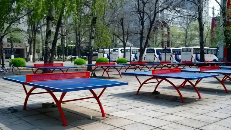 Tables de ping-pong en plein air dans un parc urbain public arboré.