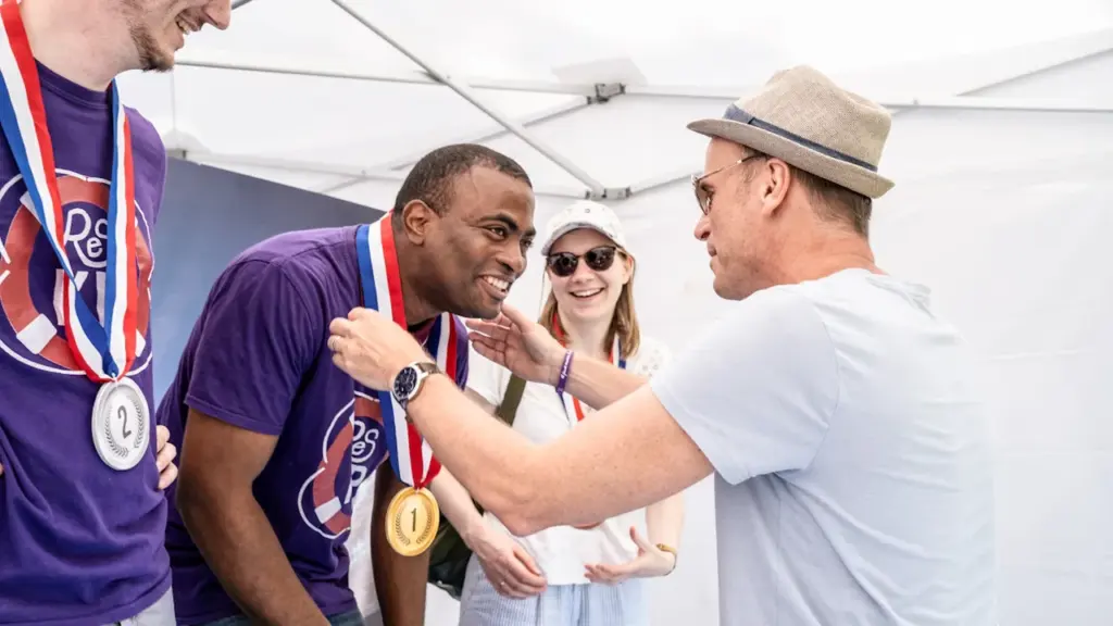 Un homme reçoit une médaille lors d'une cérémonie sportive festive en extérieur.