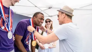 Un homme reçoit une médaille lors d'une cérémonie sportive festive en extérieur.