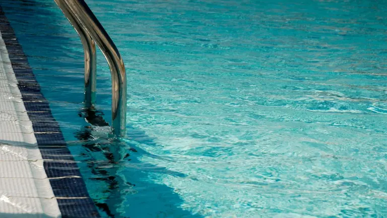 Gros plan sur le bord et l'échelle d'une piscine publique moderne.