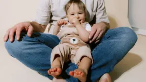 Un jeune enfant assis confortablement sur les genoux de son parent.