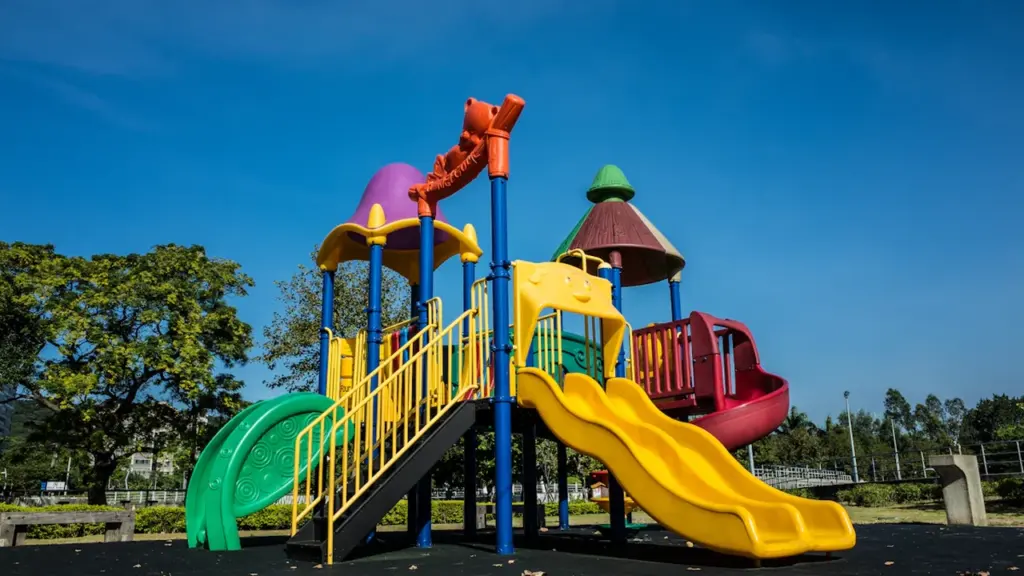 Structure de jeu colorée et inclusive installée sur un sol stabilisé en extérieur.