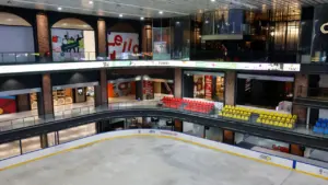 Vue plongeante sur une patinoire intérieure entourée de galeries marchandes modernes.