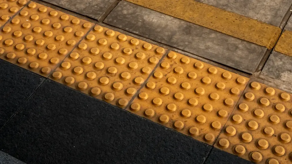 Dallage podotactile jaune au sol pour guider les personnes malvoyantes en ville.