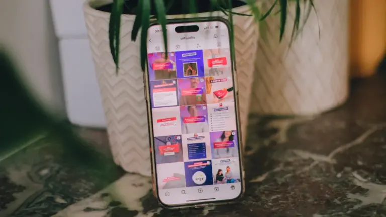 Un smartphone affichant un réseau social posé sur une table près d'une plante.