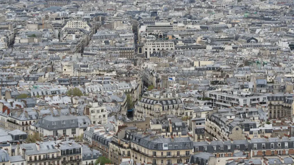 Vue aérienne panoramique des toits parisiens denses lors d'une journée lumineuse.