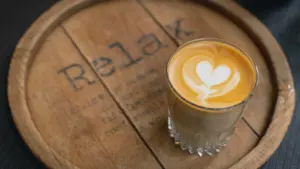 Un café latte dans un verre posé sur un plateau en bois rustique.
