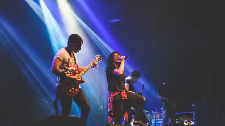 Un groupe de rock jouant sur une scène sous des projecteurs lumineux.