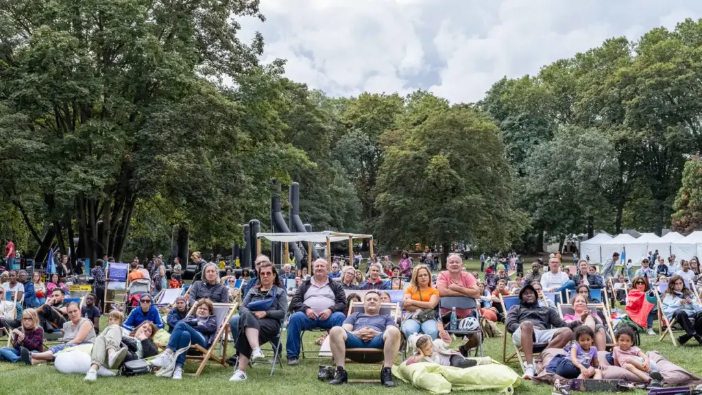 Un groupe diversifié de personnes est assis sur des chaises longues dans un parc verdoyant.