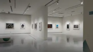 Galerie d'art contemporain lumineuse avec des tableaux accrochés aux murs blancs.