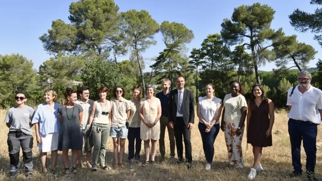Un groupe diversifié de personnes pose devant une forêt sous un ciel bleu clair.