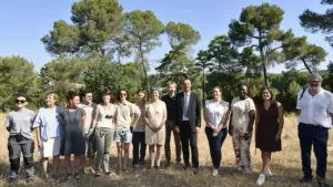 Un groupe diversifié de personnes pose devant une forêt sous un ciel bleu clair.