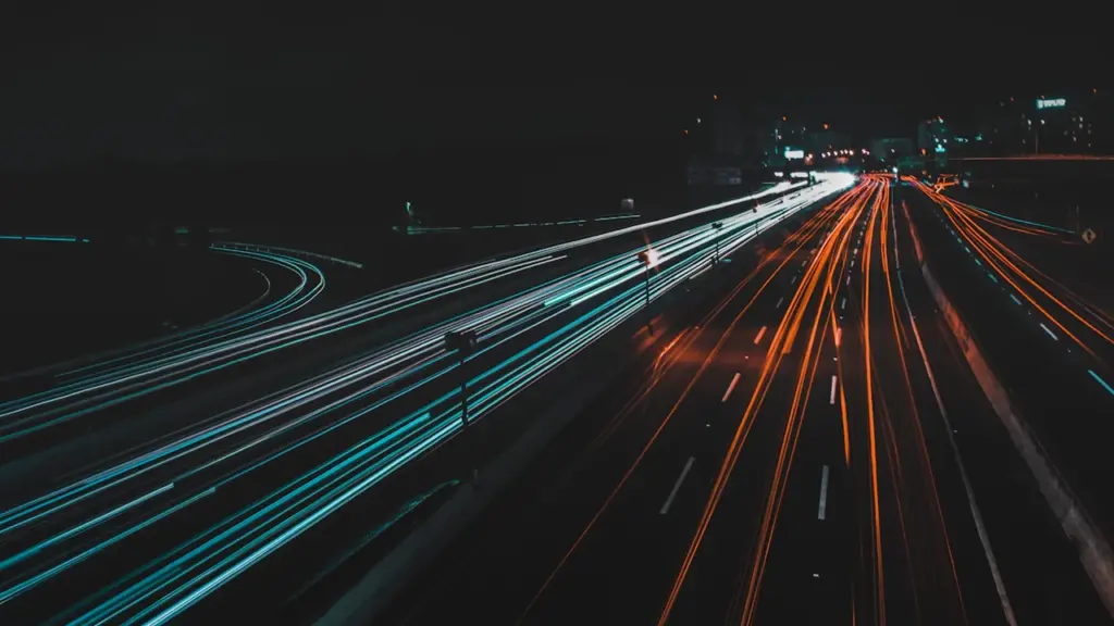 Photographie en pose longue du trafic routier sur une autoroute éclairée la nuit.