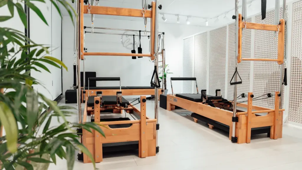 Une salle de sport équipée de machines de Pilates en bois et métal.