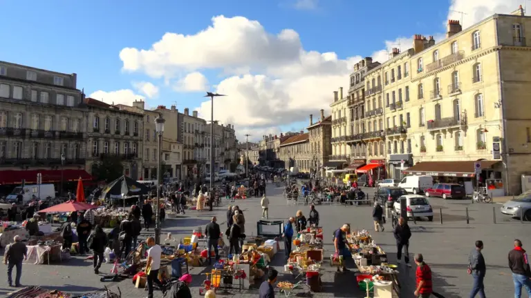 Vue d'ensemble d'une brocante animée sur une grande place en plein air.