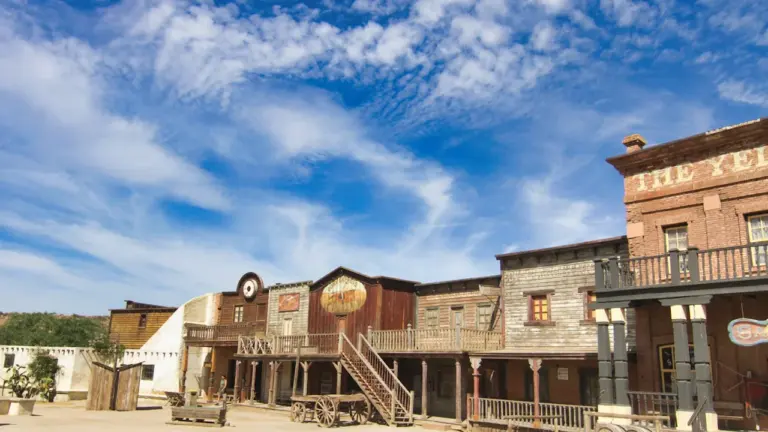 Décor de ville western avec bâtiments en bois sous un ciel bleu ensoleillé.