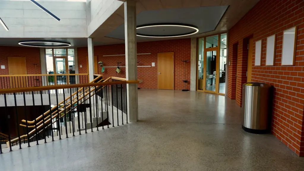 Architecture moderne d'un établissement scolaire avec escaliers et murs en briques.