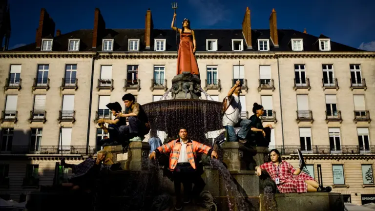 Un groupe de jeunes adultes posant devant une fontaine classique à Lyon.