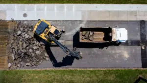 Vue aérienne d'une pelleteuse retirant l'asphalte d'une route urbaine en chantier.