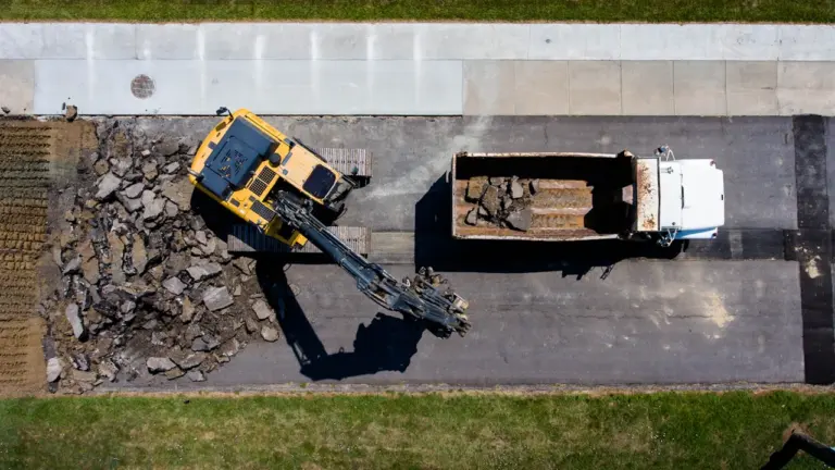 Vue aérienne d'une pelleteuse retirant l'asphalte d'une route urbaine en chantier.
