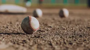 Plusieurs balles de baseball posées sur le terrain, symbolisant la discipline sportive.