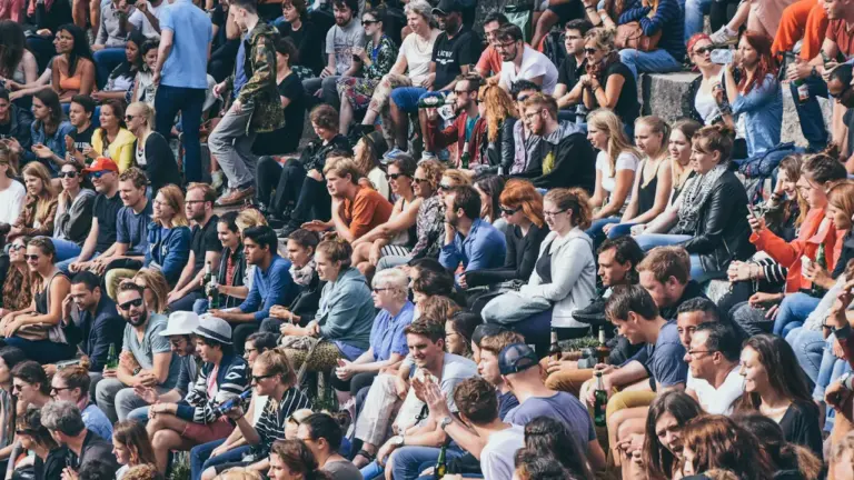 Une foule nombreuse assise dans des gradins lors d'un événement sportif en extérieur.