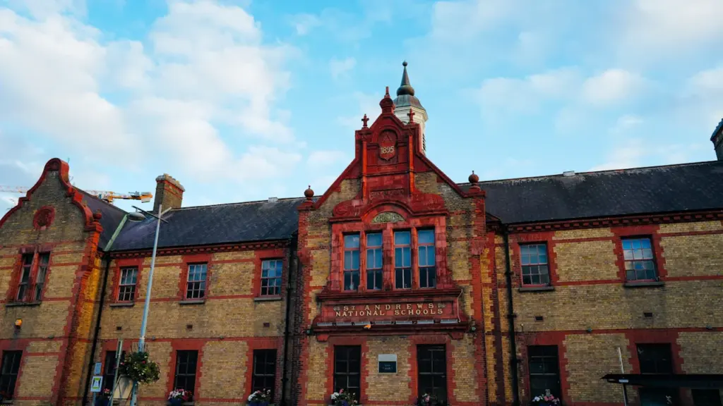 Bâtiment historique en briques rouges sous un ciel bleu dégagé pour la rentrée scolaire.
