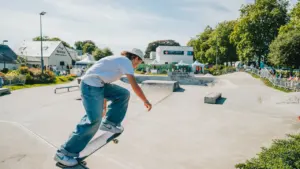 Un jeune skateur en t-shirt blanc effectue une figure sur une rampe en béton.