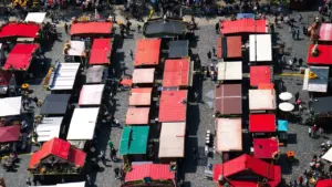 Vue aérienne d'un grand marché en plein air avec de nombreux stands colorés.