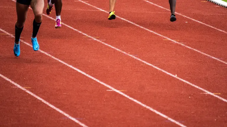 Athlètes en pleine course sur une piste d'athlétisme lors d'une compétition sportive.