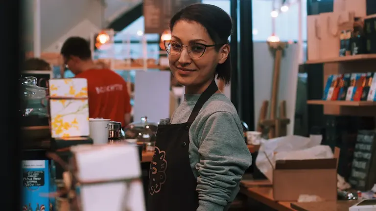 Une barista souriante derrière le comptoir d'une boutique locale à Elbeuf.