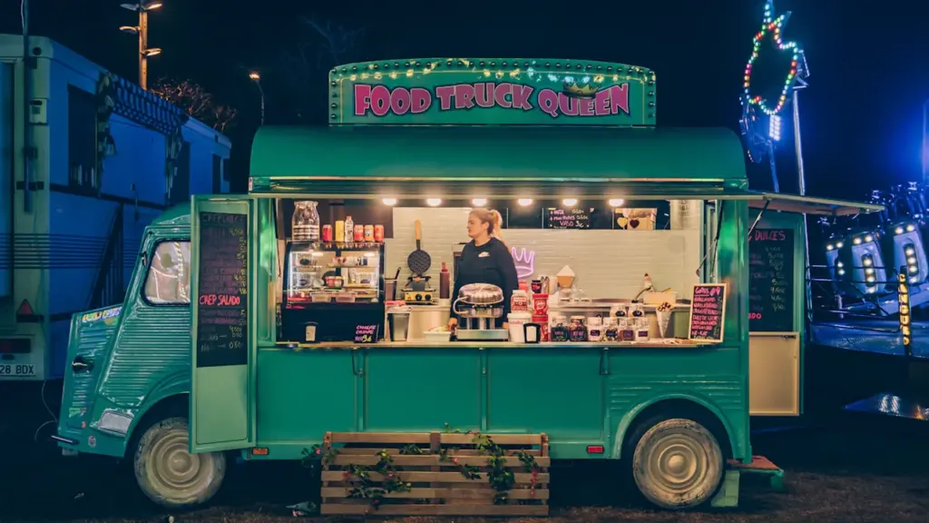 Un food truck vintage vert stationné à la tombée de la nuit.