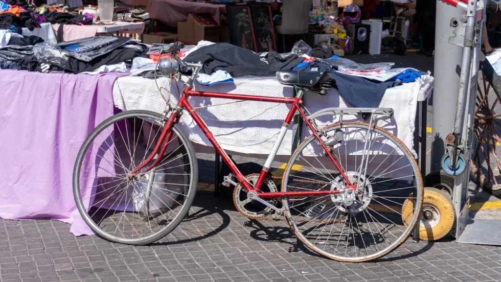 Un vélo rouge garé devant un stand lors d'une braderie en extérieur.