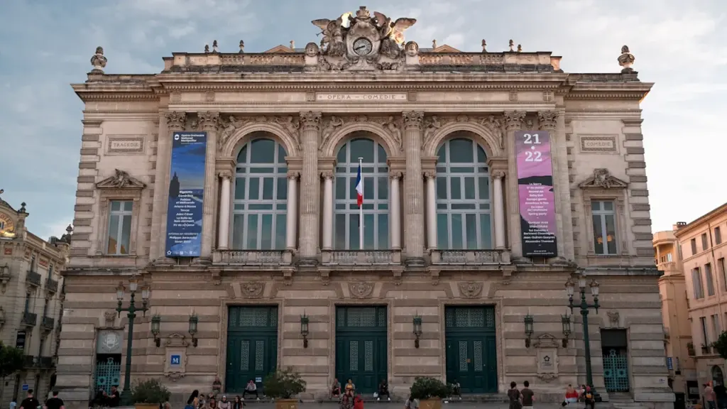 L'Opéra Comédie à Montpellier, un bâtiment historique imposant avec des passants sur la place.
