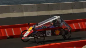 Une caisse à savon aérodynamique numérotée sur un circuit sécurisé par des barrières.