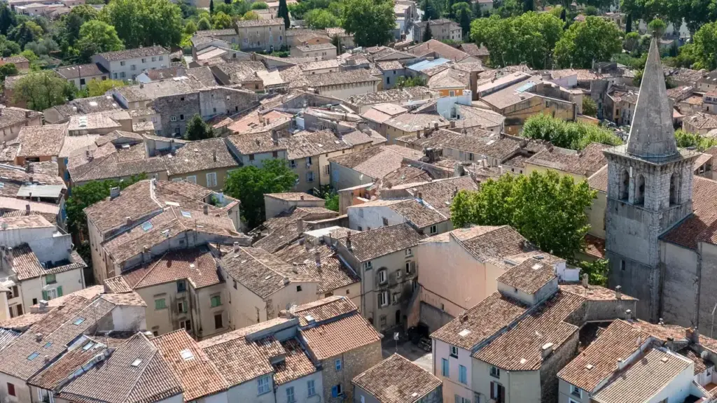 Vue aérienne d'un village français ancien avec des toits en tuiles et un clocher.
