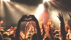 Foule enthousiaste assistant à un concert avec des mains formant un cœur en silhouette.